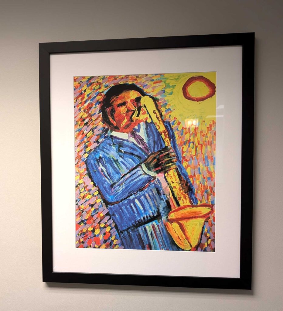 A framed painting of a person playing a saxophone, characterized by bold colors and dynamic brushstrokes.